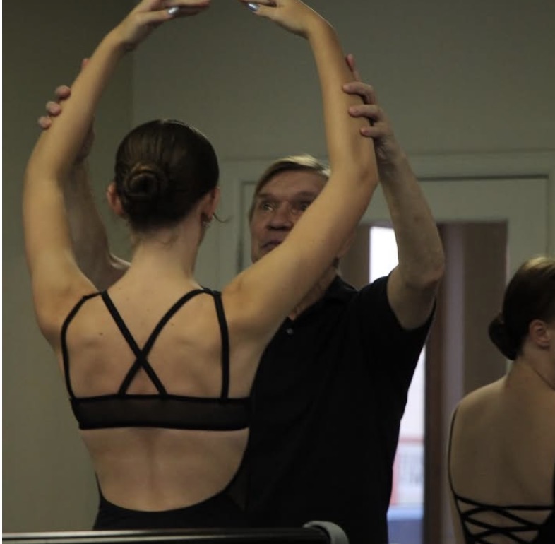 Instructor guiding a dancer’s arm placement in ballet class